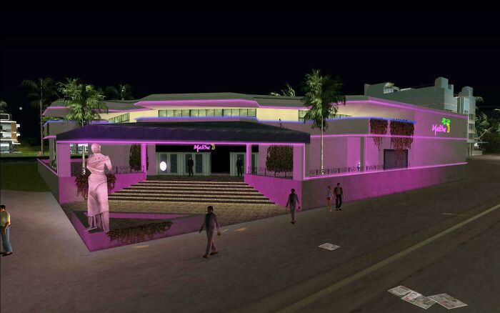 2000s Miami nightclub with pink lighting and palm trees, featuring a statue and people walking nearby.