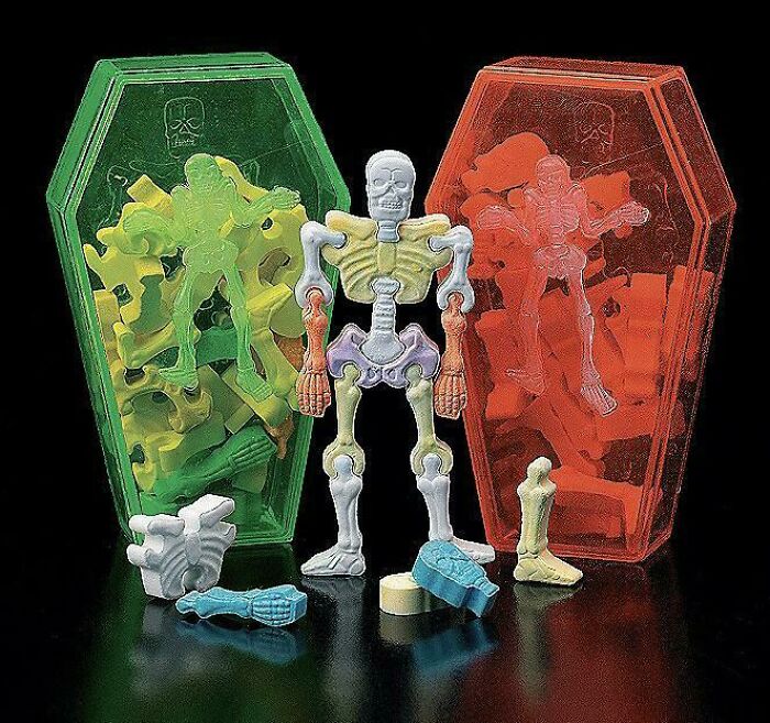 2000s nostalgic skeleton toys in colorful plastic coffins, featuring disassembled pieces on a black background.