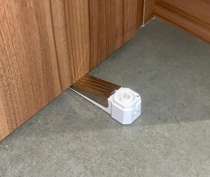 Doorstop alarm invention on a wooden floor, showcasing clever design to prevent frustration.