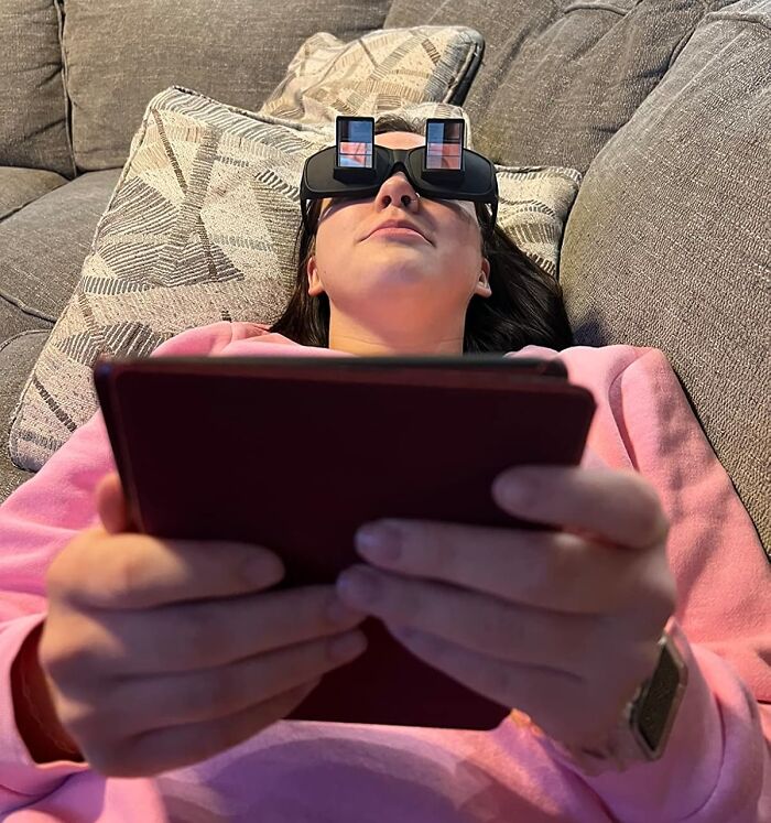 Person wearing prism glasses for reading while lying down, demonstrating clever inventions to reduce frustration.
