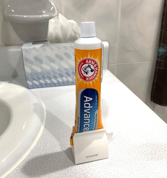 Toothpaste tube in a clever invention stand to reduce frustration on a bathroom counter.