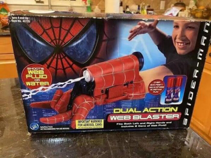 2000s nostalgia with a Spider-Man web blaster toy in original packaging, showing a smiling child playing.