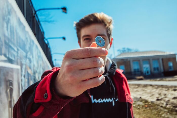 A person holding a coin outdoors, showcasing a brilliant life hack in natural light.