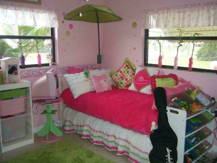Pink 2000s bedroom with bright bedding, a leaf canopy, and a vintage TV, capturing nostalgic decor elements.