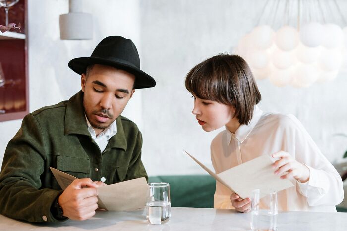 Two people reviewing a menu together at a café, sharing brilliant life hacks for dining choices.