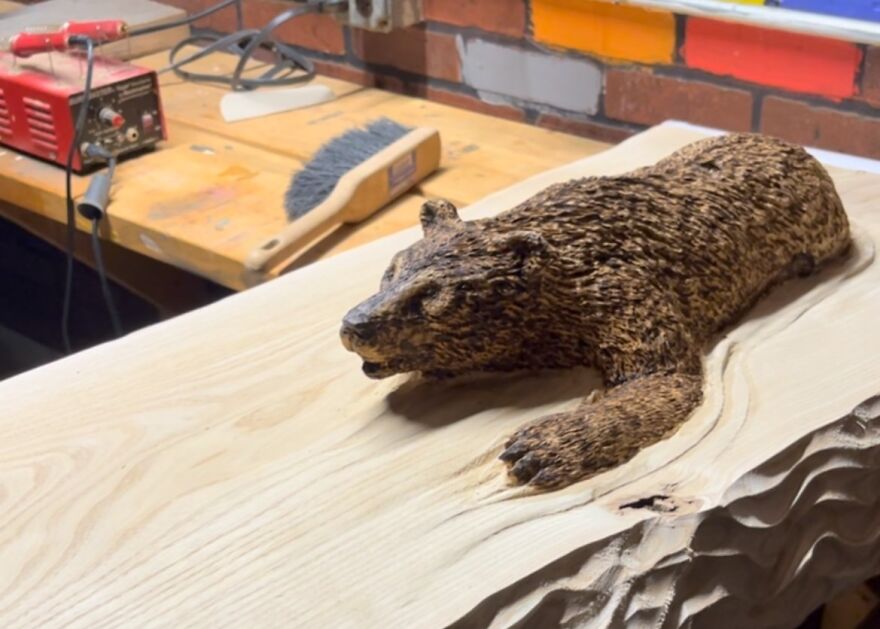 Chainsaw artist's bear sculpture on a workbench, showing intricate detail and craftsmanship.