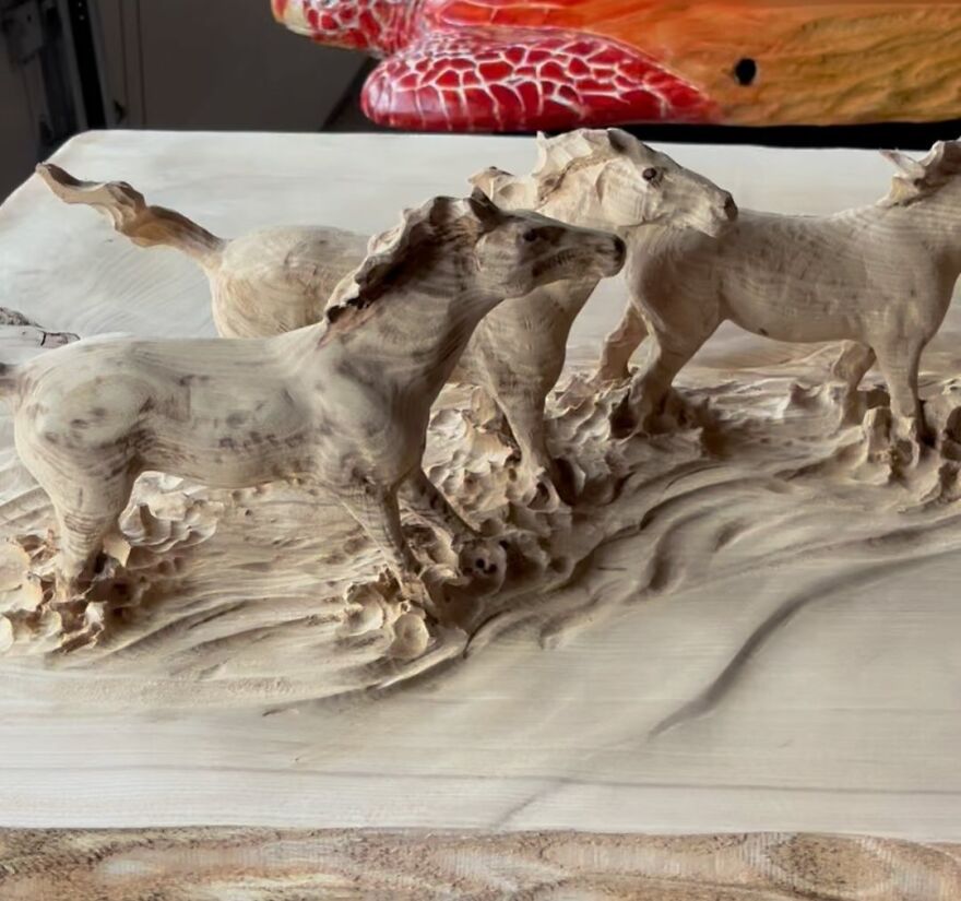 Chainsaw artist's intricate sculpture of galloping horses carved from wood.