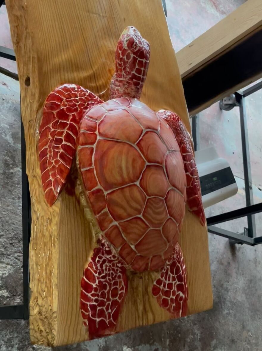 Chainsaw artist transforms log into an intricate red turtle sculpture.