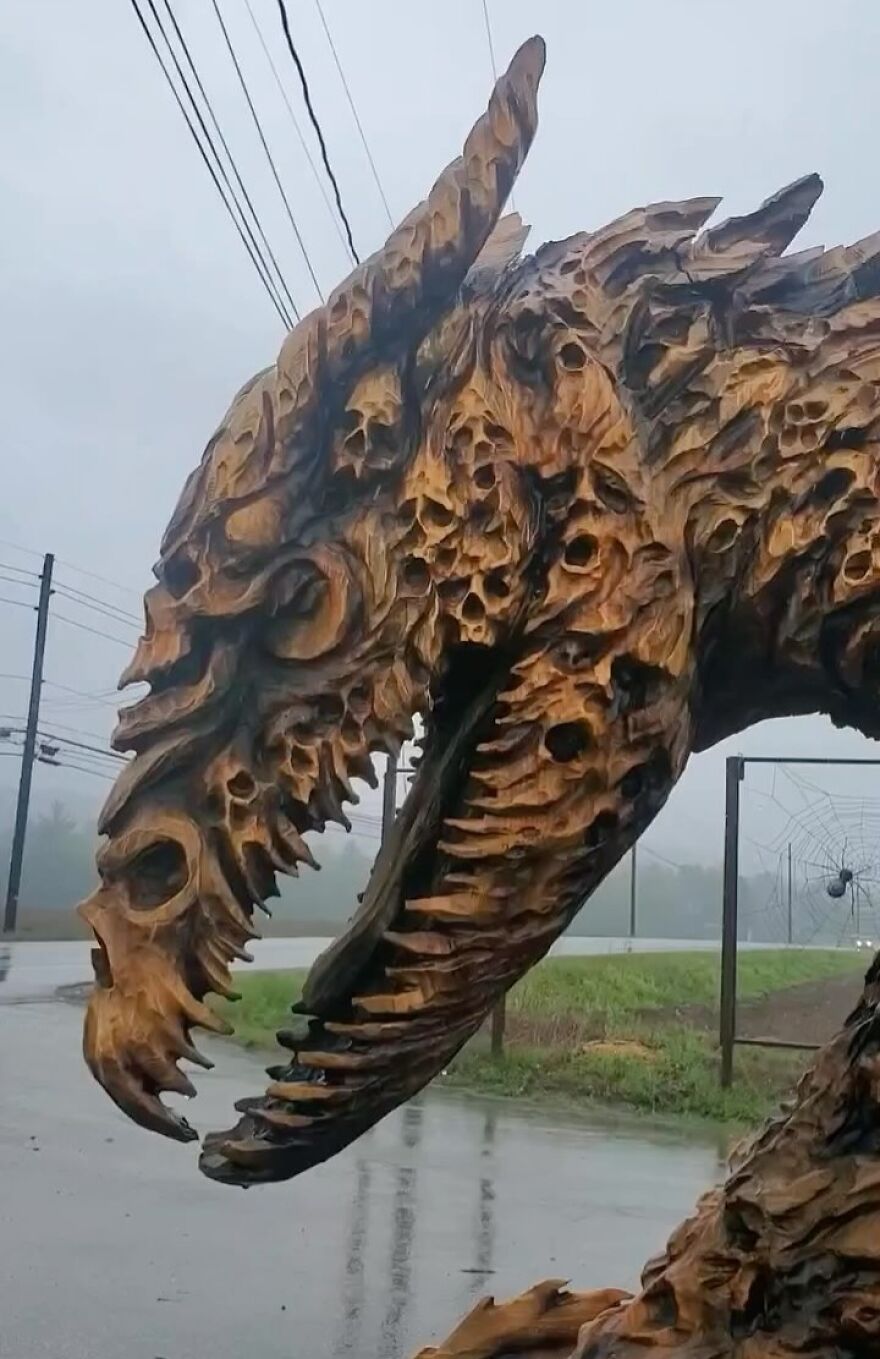 Intricate dragon sculpture carved from a log by a chainsaw artist, showcasing detailed and expressive features.