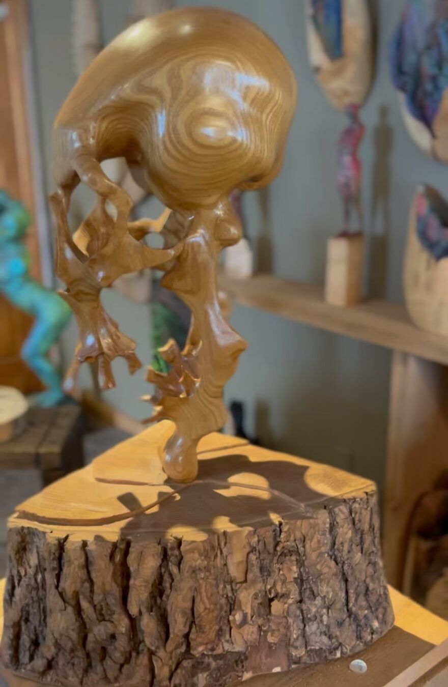 Chainsaw artist's intricate sculpture of wood, showcasing detailed craftsmanship on a tree stump base.