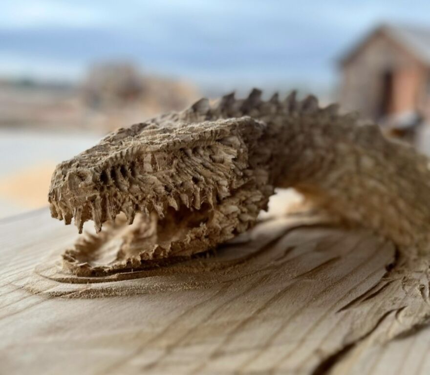 Intricate wooden sculpture by a chainsaw artist resembling a detailed dragon head.