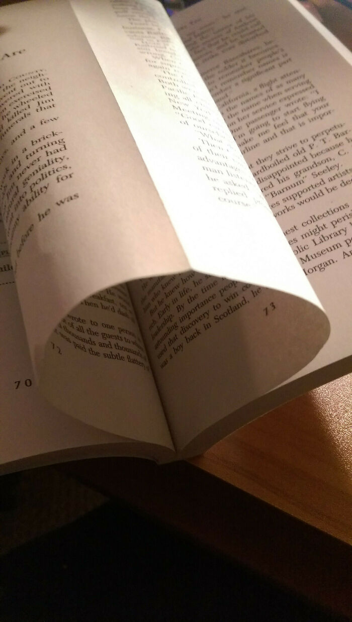 Open book with misaligned pages highlighting poorly designed books on a wooden table.
