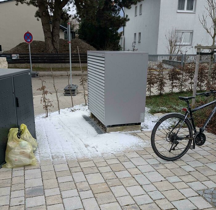 Snow only covers area around an outdoor metal structure on a paved ground, moderately interesting scene shared by people.