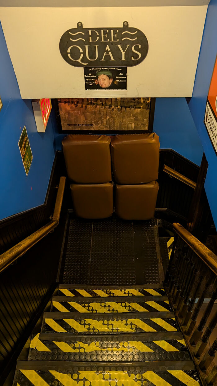 Staircase blocked by brown padded seats under a Dee Quays sign in a moderately interesting indoor setting