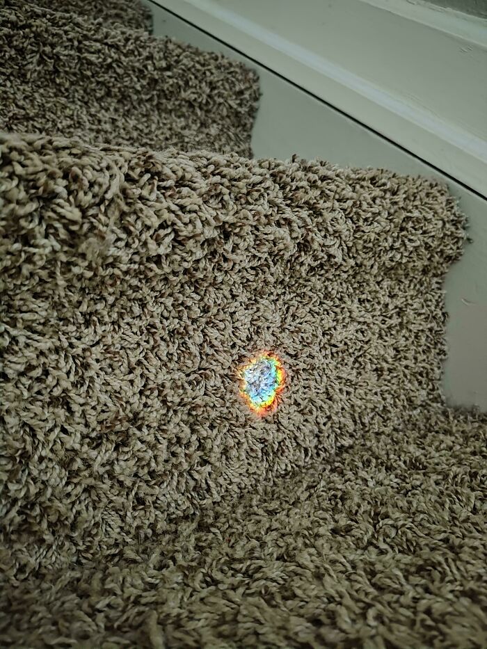 Moderately interesting rainbow light reflection on carpeted stairs creating a small colorful heart shape.