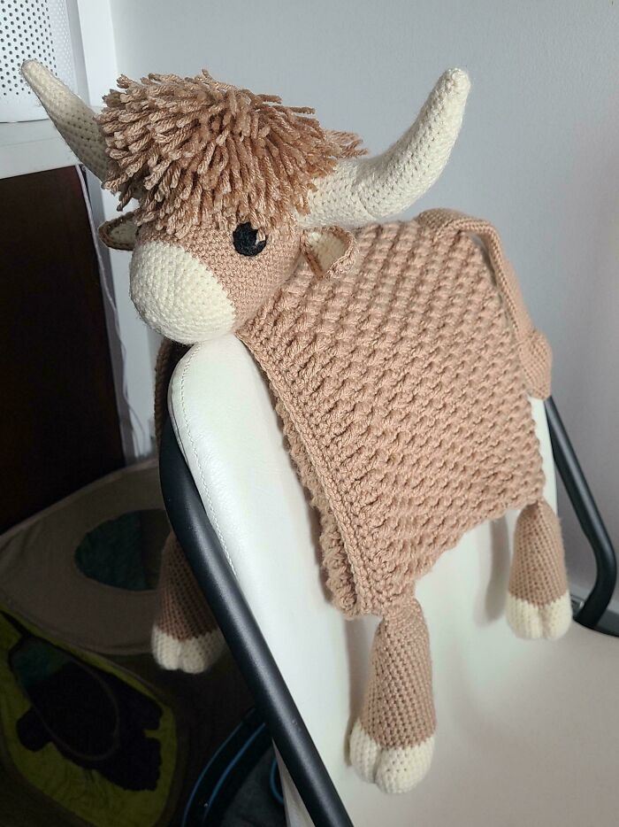 Crochet masterpiece of a bull with textured blanket draped over a chair showcasing detailed crochet work and craftsmanship.