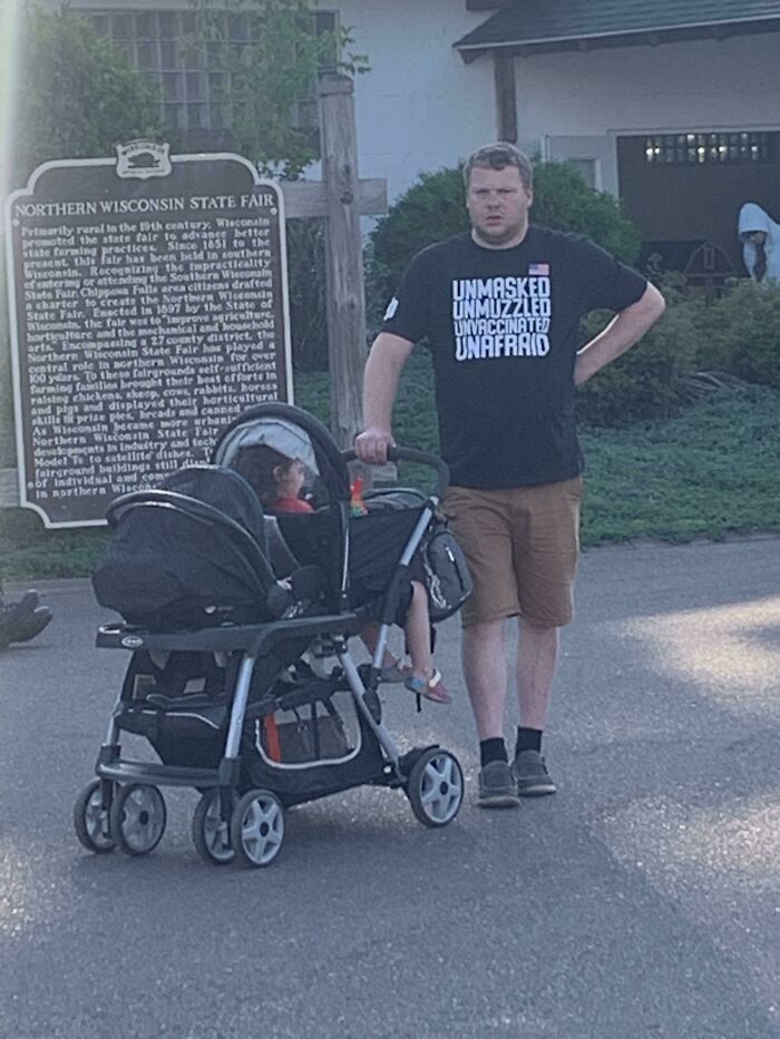 Hombre con camiseta llamativa junto a carrito de bebé, símbolo de actitud prepotente.