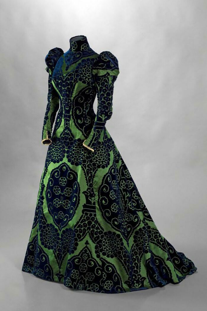 Ancient artefact dress with intricate green and blue floral patterns on display.