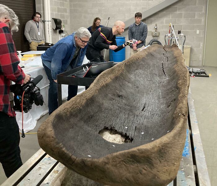 People examining ancient artefact in a lab setting, with close-up equipment focused on preservation.