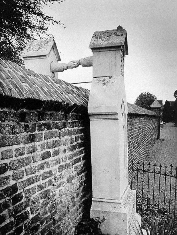 Ancient artefact showing two graves connected by clasped hands over a brick wall, symbolizing unity beyond death.