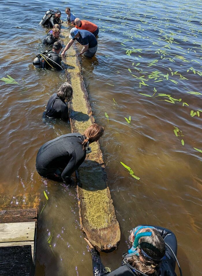Divers recover ancient artefacts submerged in a lake, showcasing teamwork and historical preservation.