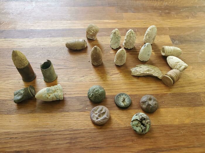 Ancient artefacts including bullets and coins displayed on a wooden surface.