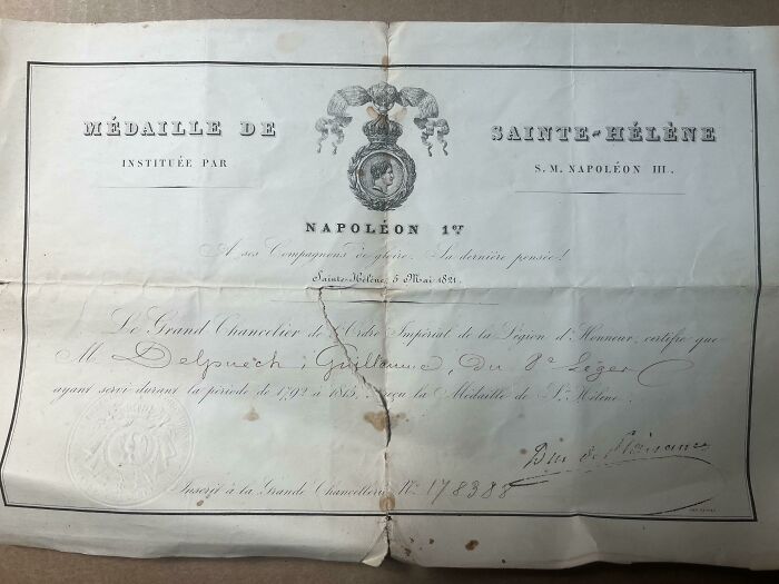 Ancient artefact document from Napoleonic era, featuring text and emblem, slightly worn with visible creases and stains.