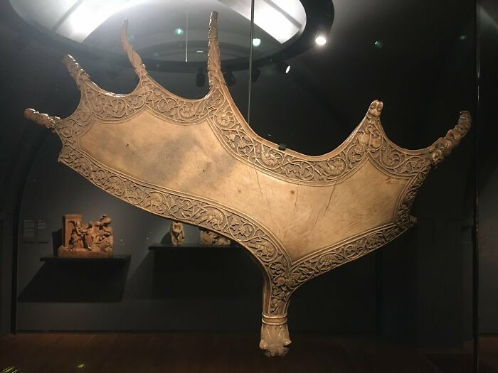 Ancient artefact with intricate carvings on display in a museum exhibit.