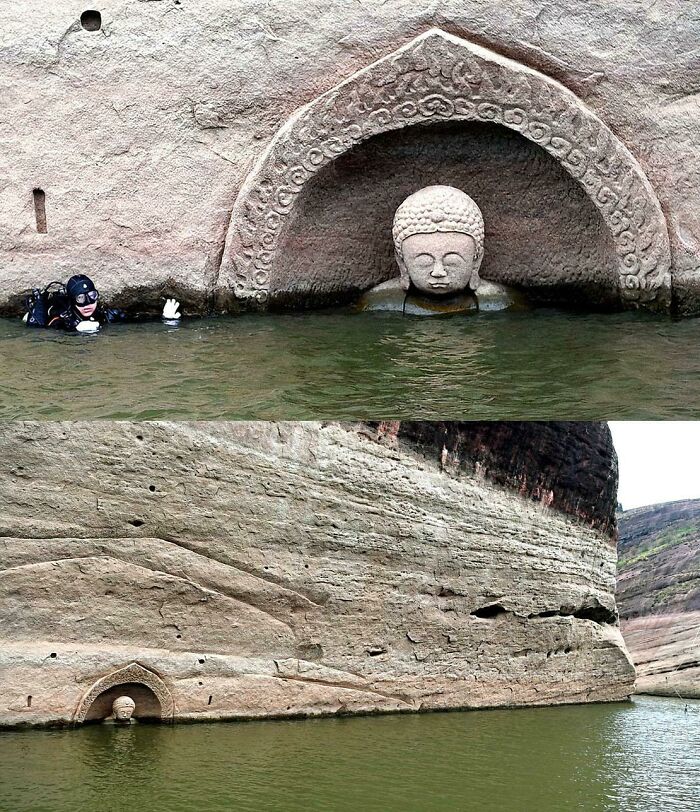 Diver next to an ancient artefact, a submerged Buddha head carved in a rock face, partially visible above the water.