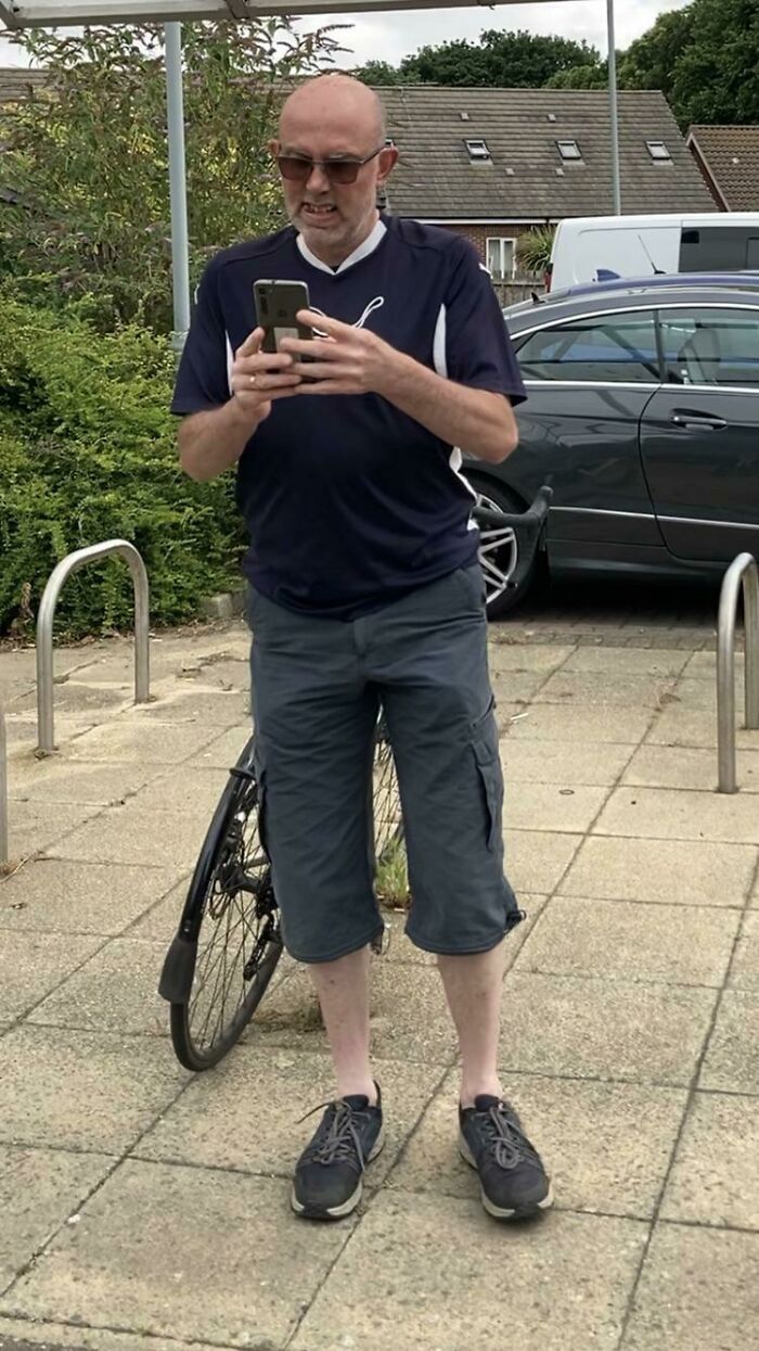 Hombre prepotente tomando fotos con su móvil en un estacionamiento, mostrando actitud seria.