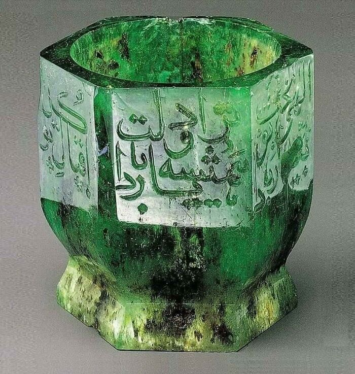 Ancient artefact: a green, ornate emerald cup with intricate writing, showcasing incredible preservation.