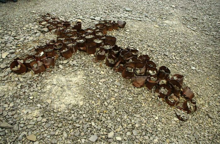 Ancient artefacts arranged in a cross shape on gravel, showcasing remarkable preservation through time.