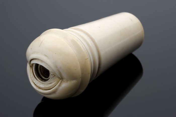 Ancient artefact, a cylindrical ivory object, displayed on a reflective surface.