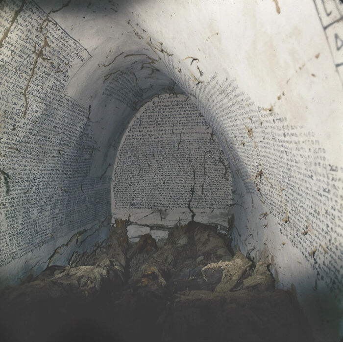 Ancient artifacts in a stone chamber with walls covered in inscriptions, showcasing remarkable preservation.