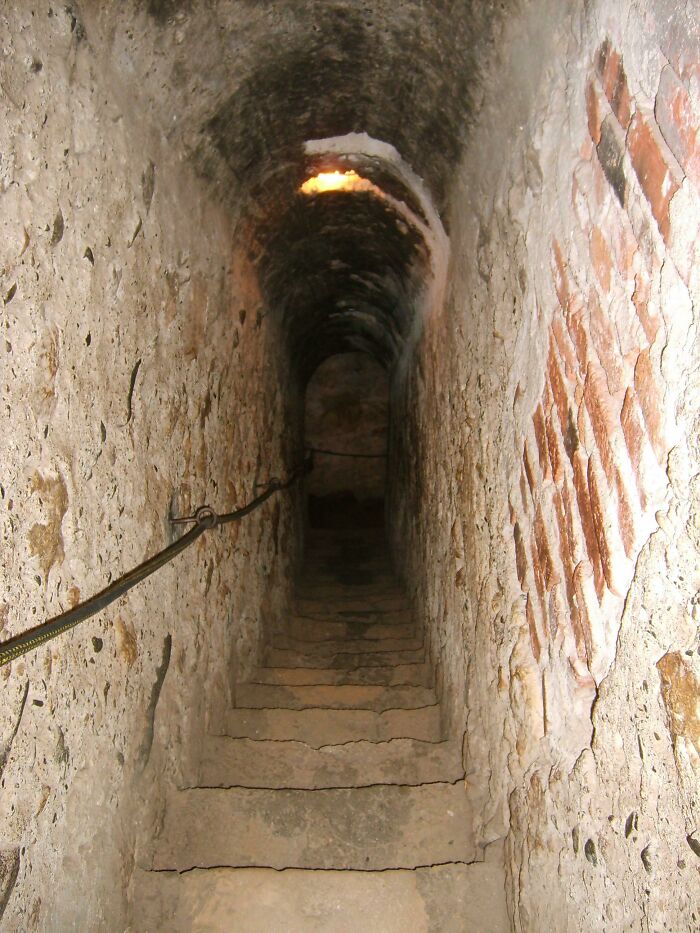 Ancient artefacts: A narrow, ancient stone staircase with brick-lined walls, descending into the darkness.