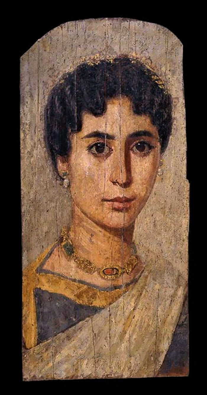 Ancient artefact of a woman in traditional attire with ornate jewelry, painted on wood.
