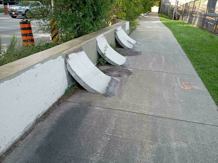 Weird objects found on a sidewalk, featuring unusual concrete structures next to metal grates.