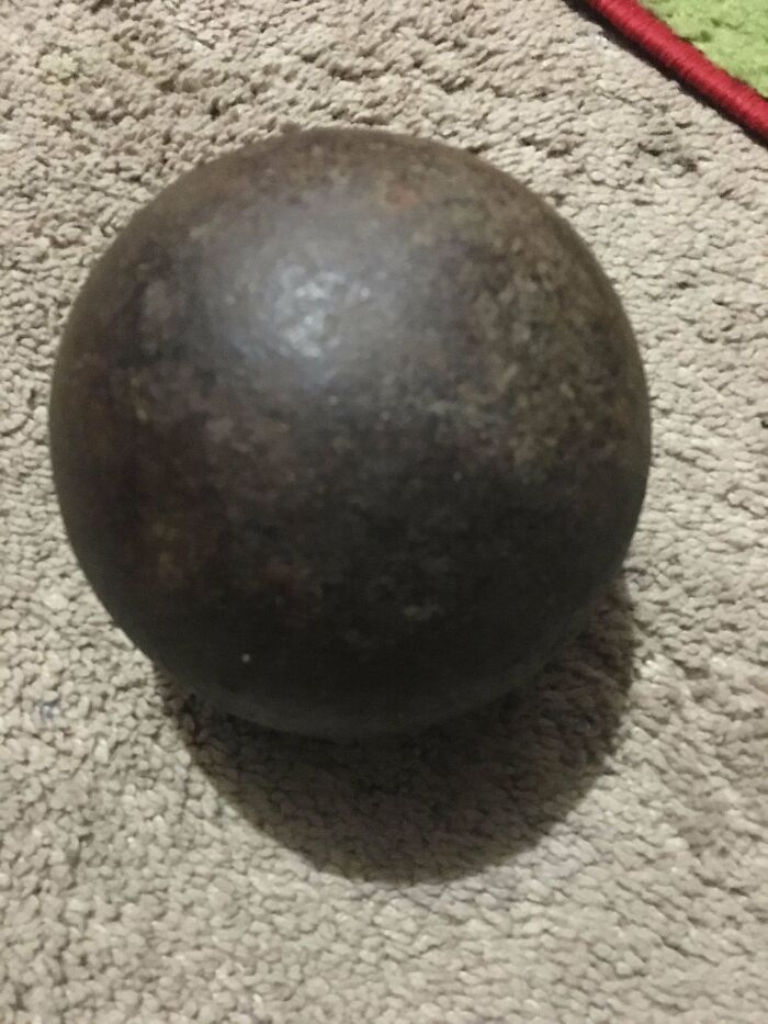 A mysterious round object found on a textured surface, possibly a cannonball.