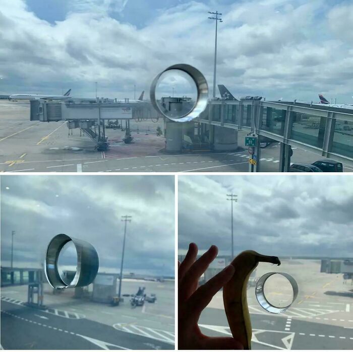 Weird object at airport window with circular design; person holds banana next to it for scale.