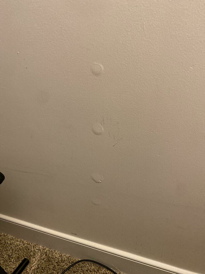 Indentations on a wall near the floor, resembling unexplained weird objects or markings.