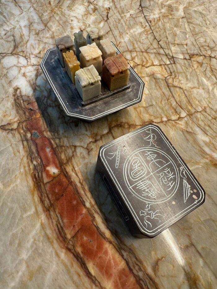 Weird object with carved stone pieces and an ornate box on a marble surface.