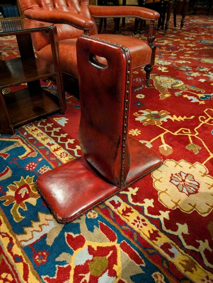 Weird object with red leather design on a colorful vintage carpet in a furnished room.