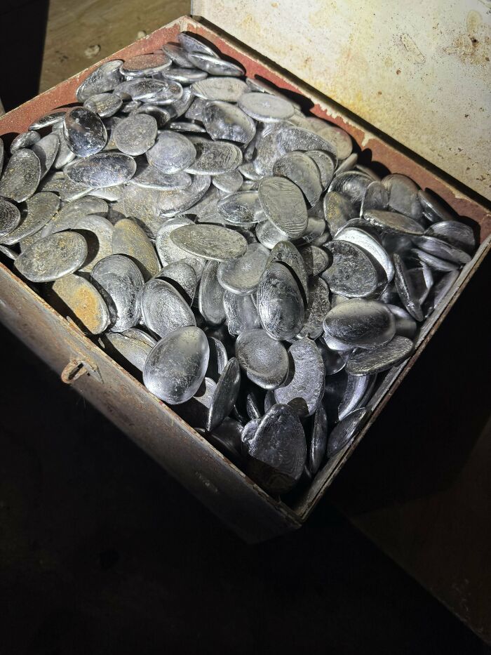 A box filled with numerous shiny, metallic oval objects discovered, causing curiosity about their purpose and origin.