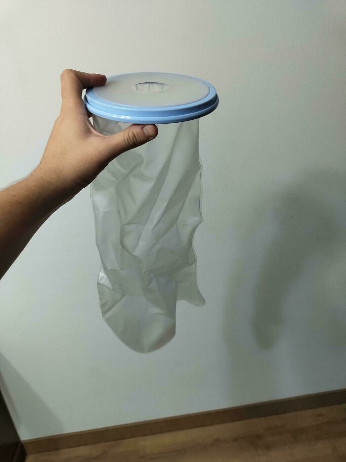 Person holding a mysterious translucent object with a blue rim, resembling a plastic sock or sleeve.