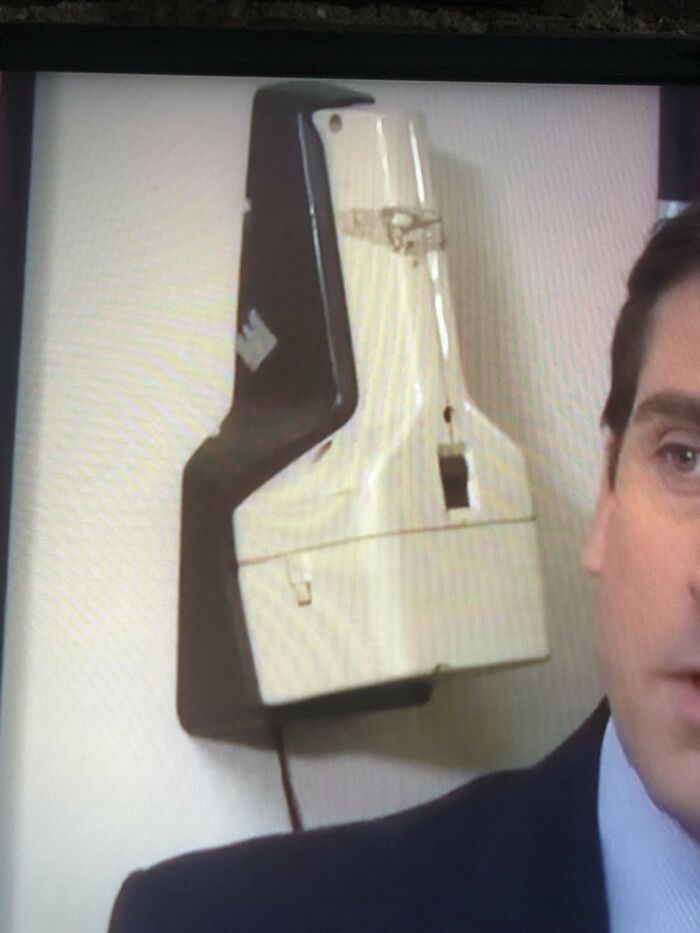 A mysterious wall-mounted device in an office setting, partially obscured by a person.