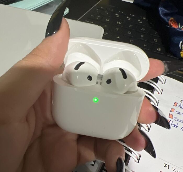 AirPods in a charging case held by a person, possibly the best gift they've received.