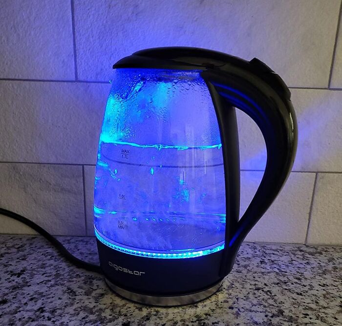 Electric kettle with blue LED light on a countertop, showcasing a modern kitchen appliance.