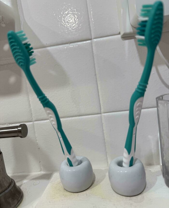 Teal toothbrushes in holders on a tiled bathroom sink, representing annoying boyfriends' or husbands' habits.