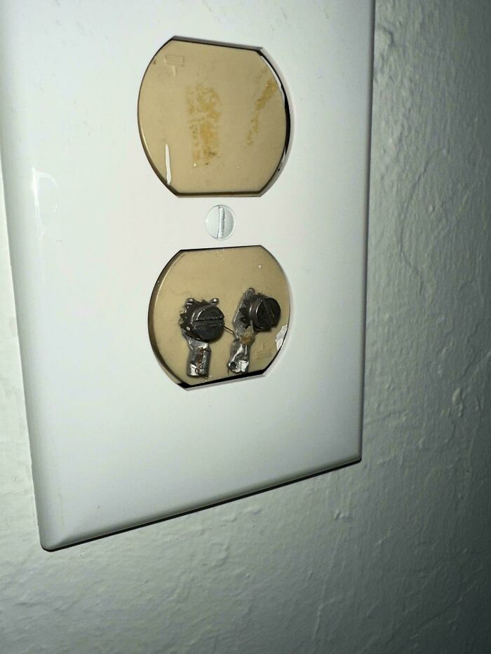 Weird object in an electrical outlet, missing covers, showing inner components against a wall.