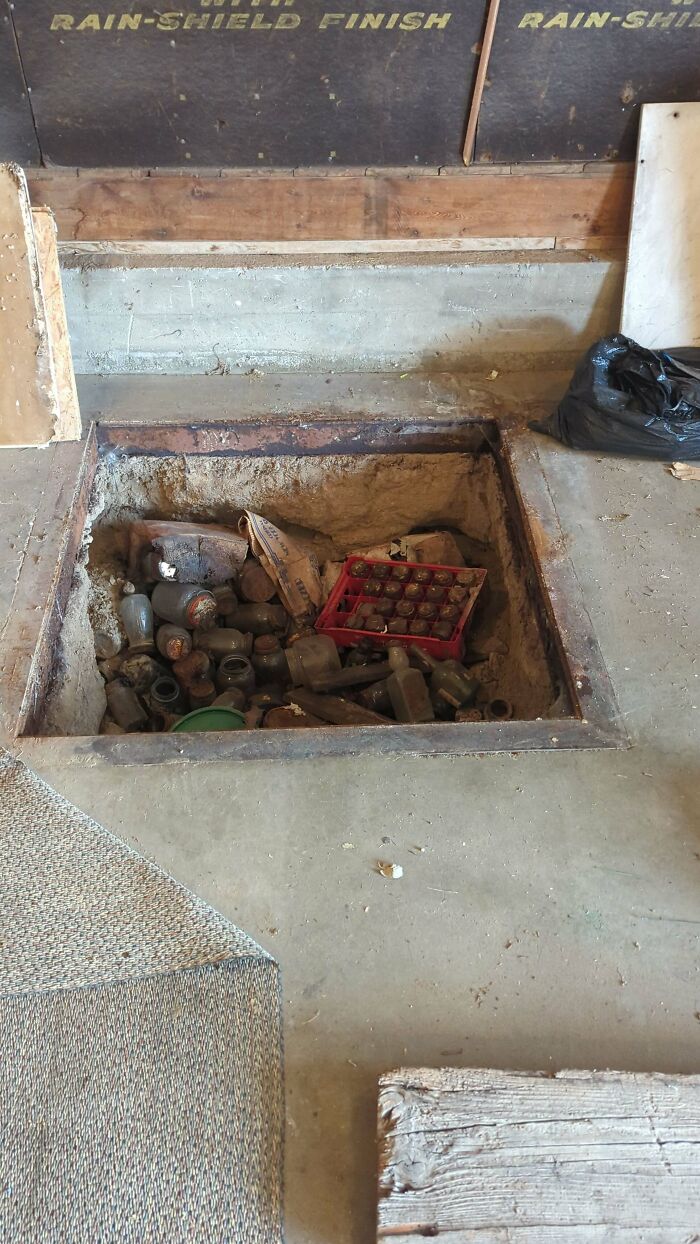 Hidden storage cavity with bottles and boxes, covered by a rug, showcasing a weird object discovery.